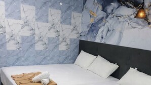 A hotel room with a large bed, a marble-patterned wall, and a hanging light fixture. - Port Dickson Seafront Hotel (Port Dickson)