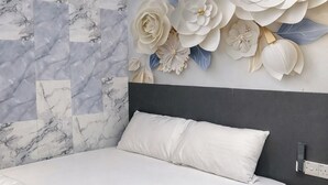A bedroom with a bed, a marble-patterned wall, and a large floral decoration. - Port Dickson Seafront Hotel (Port Dickson)