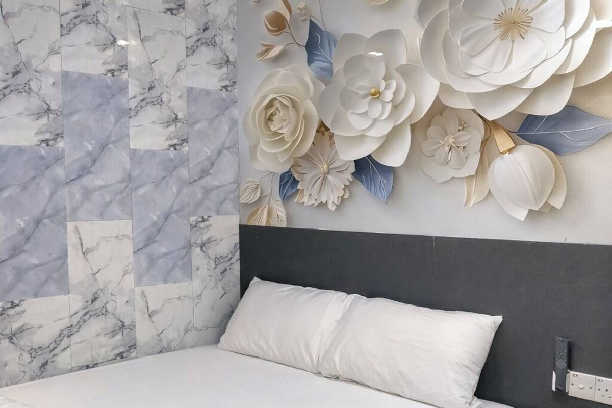 A bedroom with a bed, a marble-patterned wall, and a large floral decoration.
