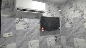 A bathroom with a white air conditioner, a mounted television, and a wall-mounted fire alarm. - Port Dickson Seafront Hotel (Port Dickson)