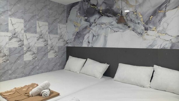 A hotel room with a bed, a headboard, and a marble-patterned wall. - Port Dickson Seafront Hotel (Port Dickson)