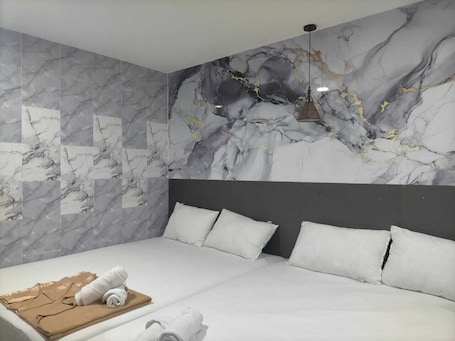 A hotel room with a bed, a headboard, and a marble-patterned wall.