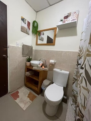 Ein kleines Badezimmer mit Toilette, Waschbecken und einem Spiegel darüber.