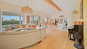 A spacious living area with a curved sofa, wooden beams, and a view of the outdoors. - Villa La Carqueiranaise (CARQUEIRANNE)