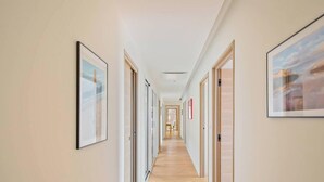 A long, narrow hallway with framed pictures on the walls, wooden doors, and a view into a room at the end. - Villa La Carqueiranaise (CARQUEIRANNE)