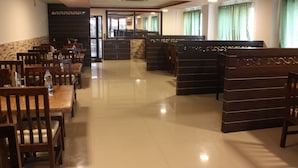 Ein Restaurant mit Holztischen und -stühlen, einem Fliesenboden und einer Theke.