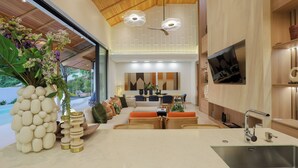 Una cocina moderna con horno empotrado, una isla grande con fregadero y un área de comedor con sofá y sillas.