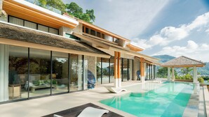 Una casa moderna con piscina, amplias ventanas y vistas a las montañas.