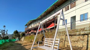 A building with a balcony and a swing set in front.
