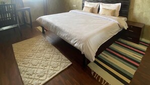 A bedroom with a bed, a nightstand, a chair, a window, and a patterned rug.