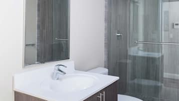 A modern bathroom with a glass shower enclosure, a white sink, and a toilet.