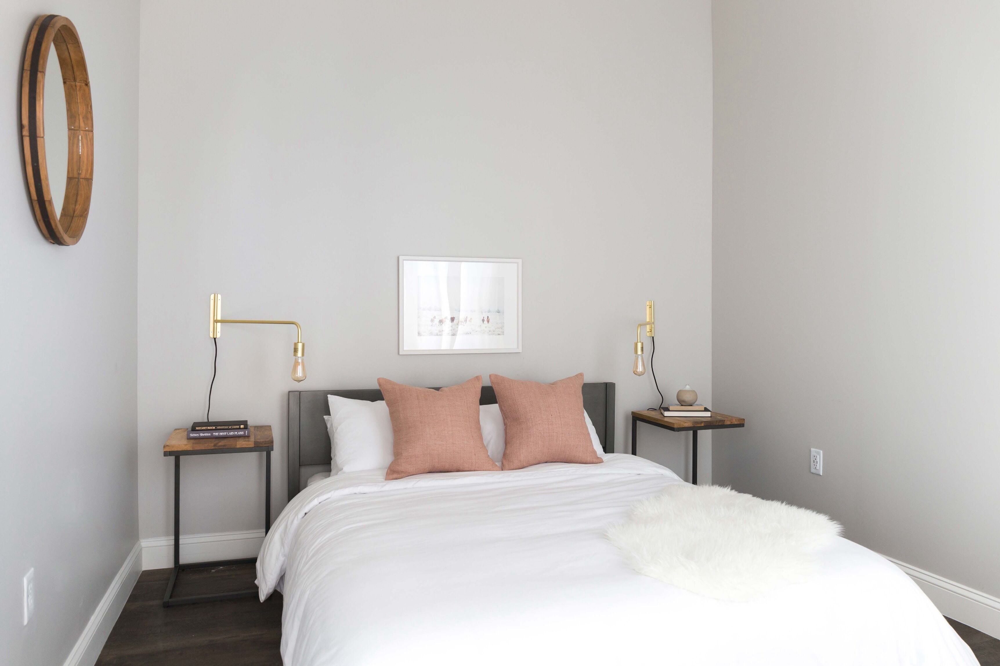 Quarto com cama, duas mesas de cabeceira, um quadro na parede e um lustre.