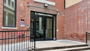 Edifici de maó amb una porta negra amb la inscripció '6 Hamilton Place'. Hi ha càmeres de seguretat i un senyal de 'Prohibida l'entrada' a la paret.