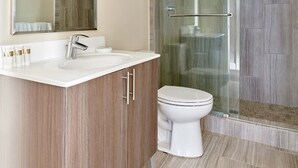 Un bany modern amb una cabina de dutxa de vidre, un mirall gran i un moble de bany amb rentapelats i armari.