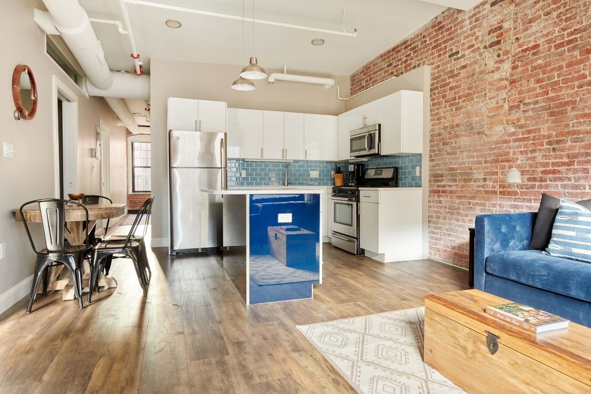Cocina moderna con armarios blancos, un refrigerador de acero inoxidable y un salpicadero de azulejos azules.