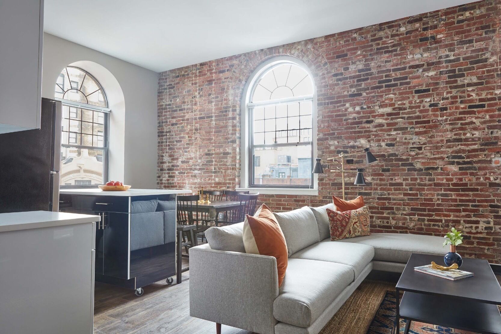 Un espacio habitable moderno con pared de ladrillo, zona de comedor y cocina.