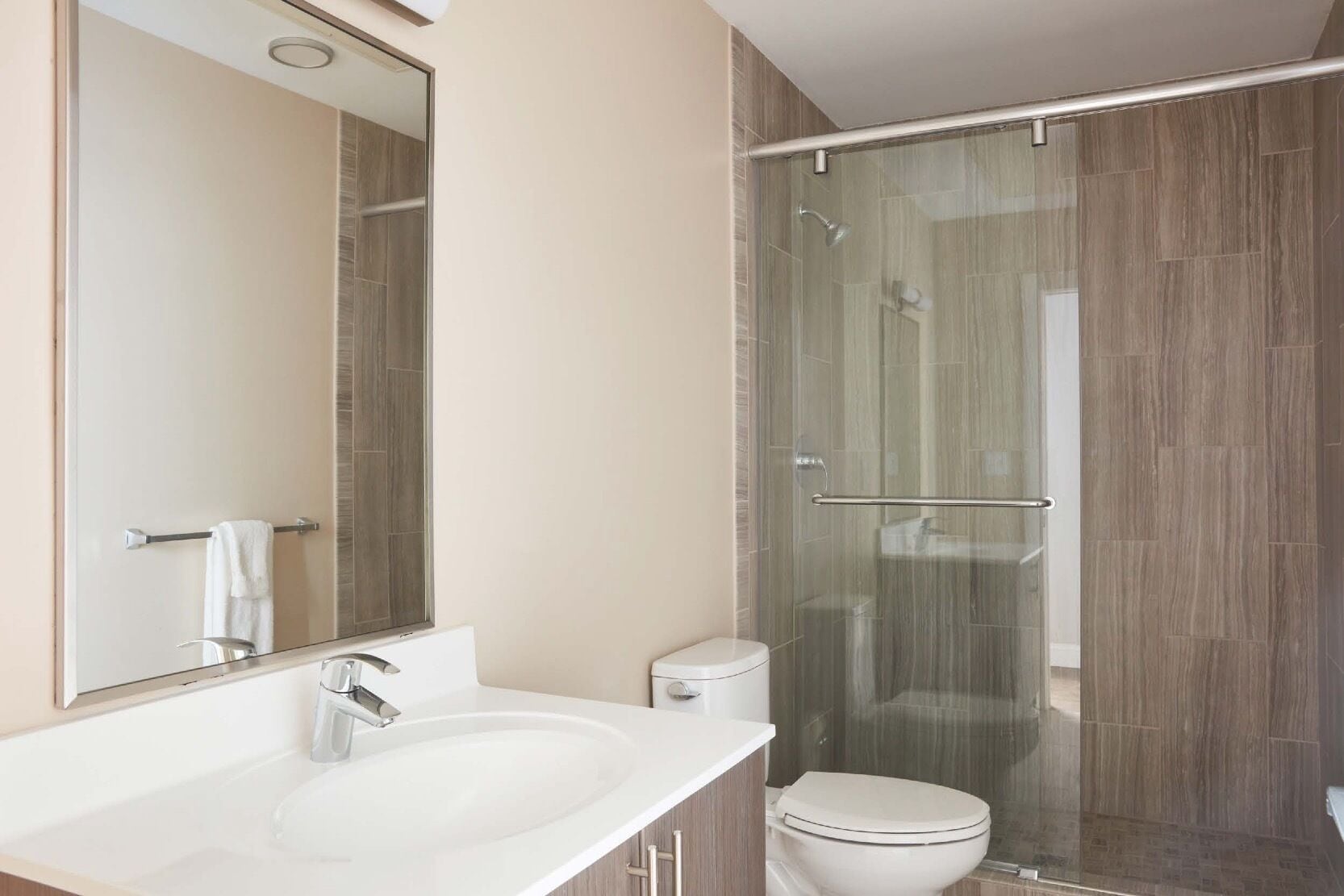 A modern bathroom with a glass-enclosed shower, a white sink, and a toilet.