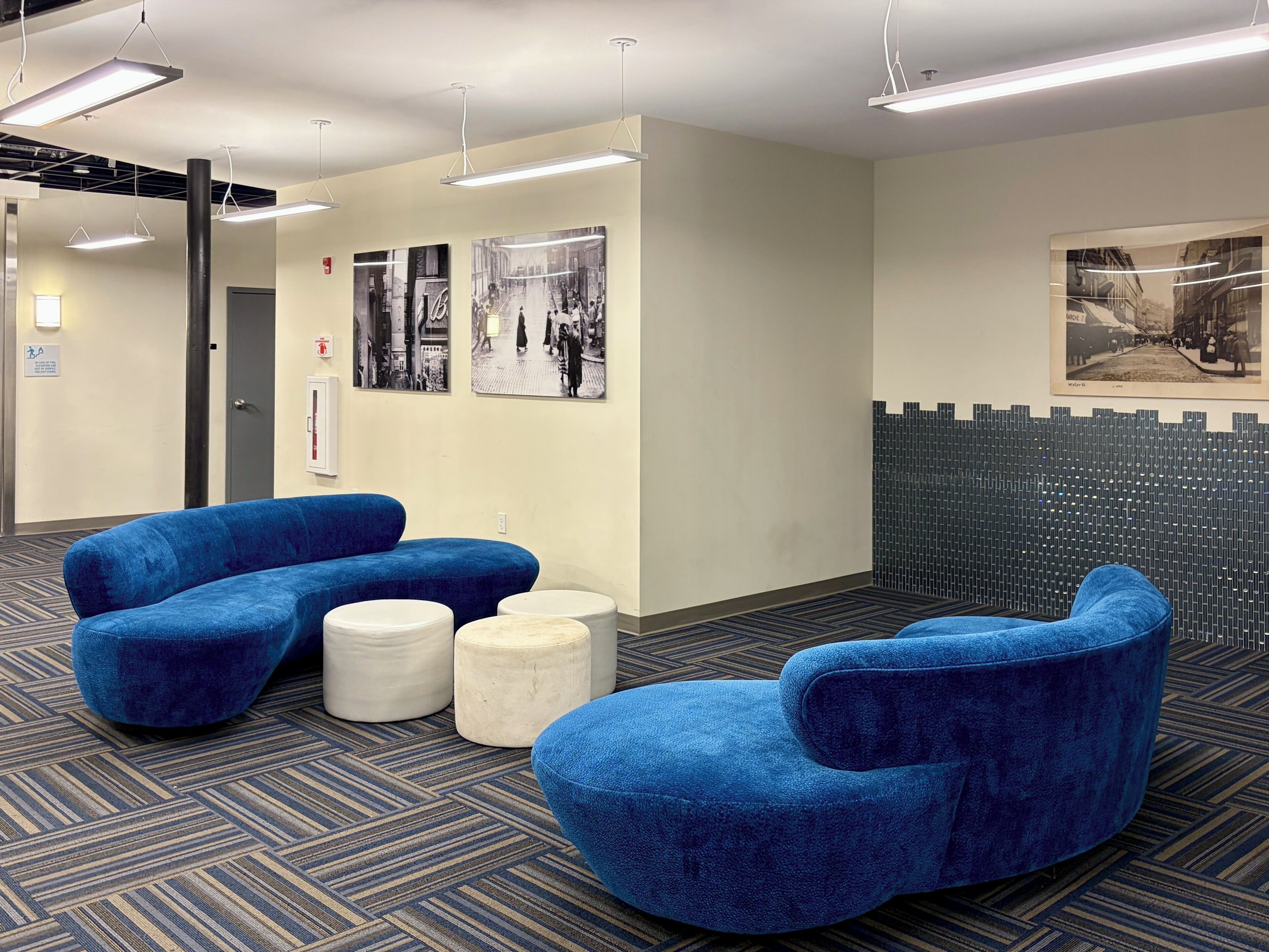 A modern waiting area with blue seating, a patterned carpet, and wall-mounted artwork.