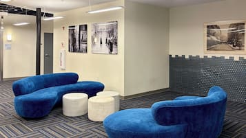 A modern waiting area with blue seating, a patterned carpet, and wall-mounted artwork.