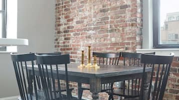 A dining area with a brick wall, a round table, and black chairs.