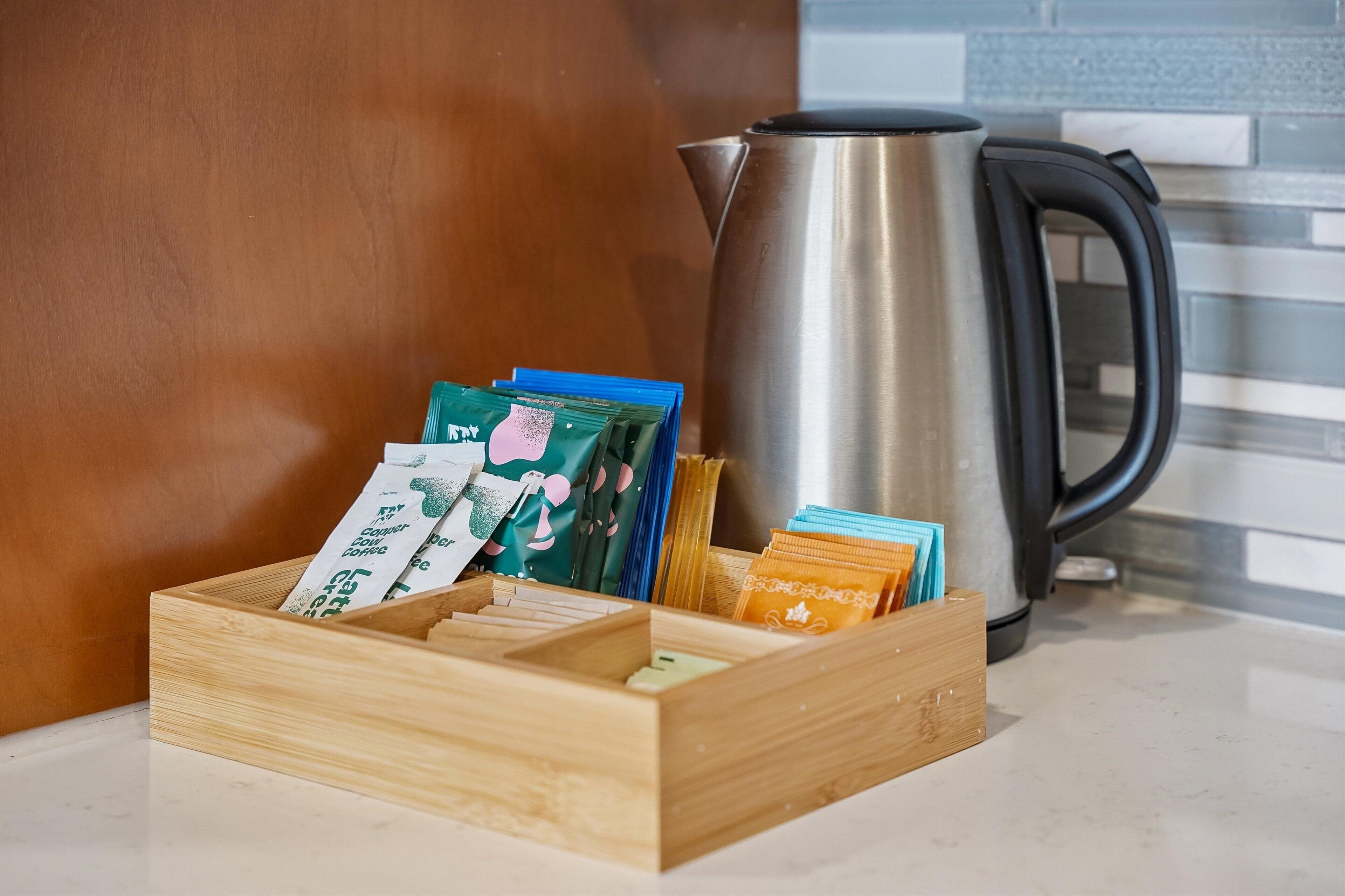 A wooden box with coffee pods and a kettle on a countertop.