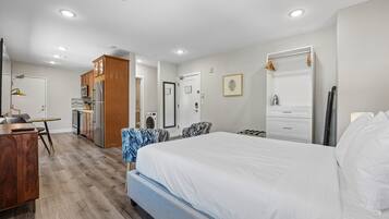 Ein Hotelzimmer mit Bett, Schreibtisch, Küchenzeile, Badezimmer und Dusche.