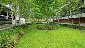 Une cour aménagée avec des arbres, un jardin central et un bâtiment en arrière-plan.