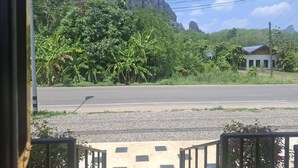 A road with a building and vegetation in the background. - Room-charming Ao Nang Guest Room 6 Bedro (Krabi)