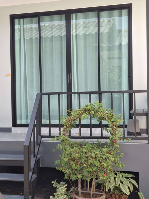 A balcony with a potted plant arrangement, a window with curtains, and a metal railing. - Room-charming Ao Nang Guest Room 6 Bedro (Krabi)
