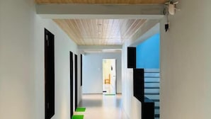 Een moderne hal met een houten plafond, een trap en zicht op een andere kamer.