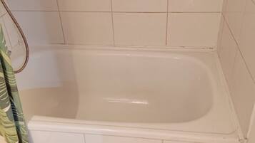 A small bathroom with a white bathtub, a toilet, and a shower curtain.