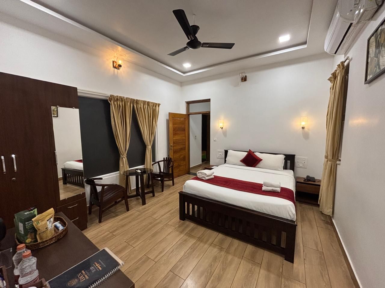 Une chambre d’hôtel équipée d’un lit, d’un bureau, d’une chaise, d’une armoire et d’un ventilateur de plafond.