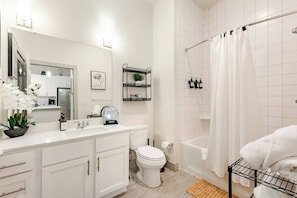 A modern bathroom with a white sink, toilet, and shower area. - Riverwalk Oasis - Pool, Free Parking & Views (San Antonio)