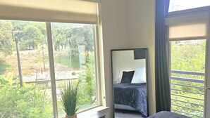 A bedroom with a large window, a bed, a dresser, and a mirror. - Riverwalk Oasis - Pool, Free Parking & Views (San Antonio)