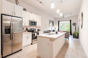 Een moderne keuken met roestvrijstalen apparatuur, een centraal eiland en een eetgedeelte met uitzicht.