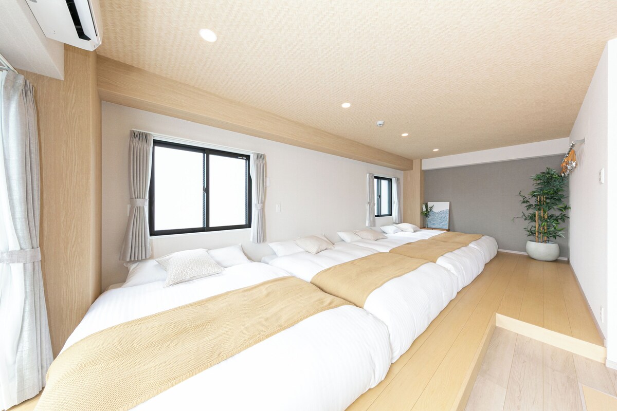 A modern hotel room with a large bed, a potted plant, and a view of the city.