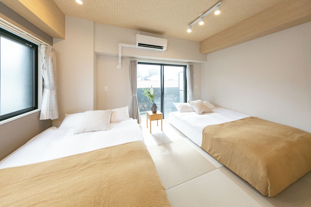A hotel room with two beds, a window, an air conditioning unit, and a view of the outside.
