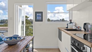 Una cocina moderna con vistas a la ciudad, un comedor con mesa de madera y un balcón con barandilla.