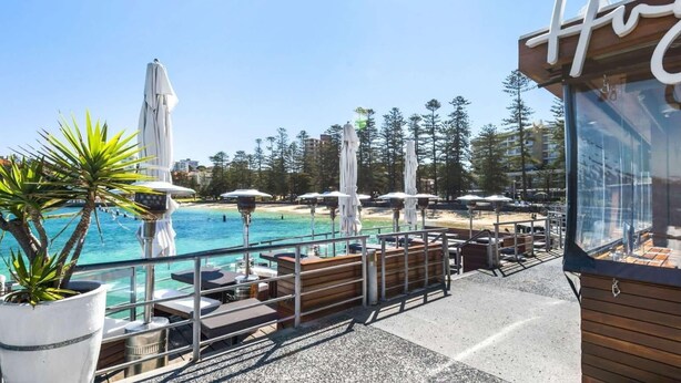 Zona de piscina con sombrillas, sillas de descanso y vistas al océano.