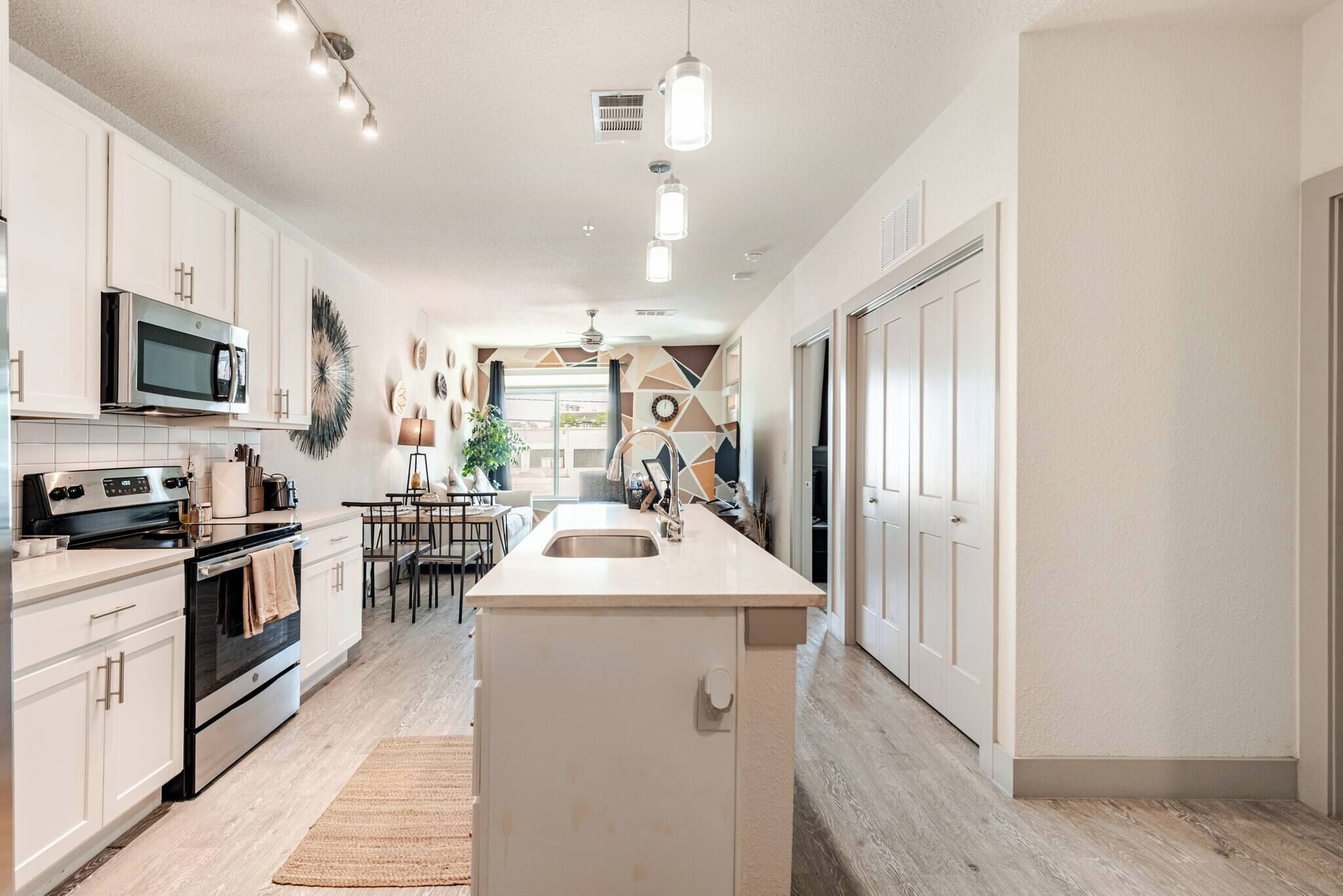 Una cocina moderna con armarios blancos, una isla central, un microondas y una estufa.