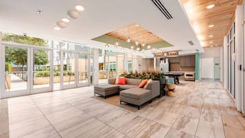 A spacious living area with a sectional sofa, a kitchen in the background, and large glass doors leading to an outdoor patio.