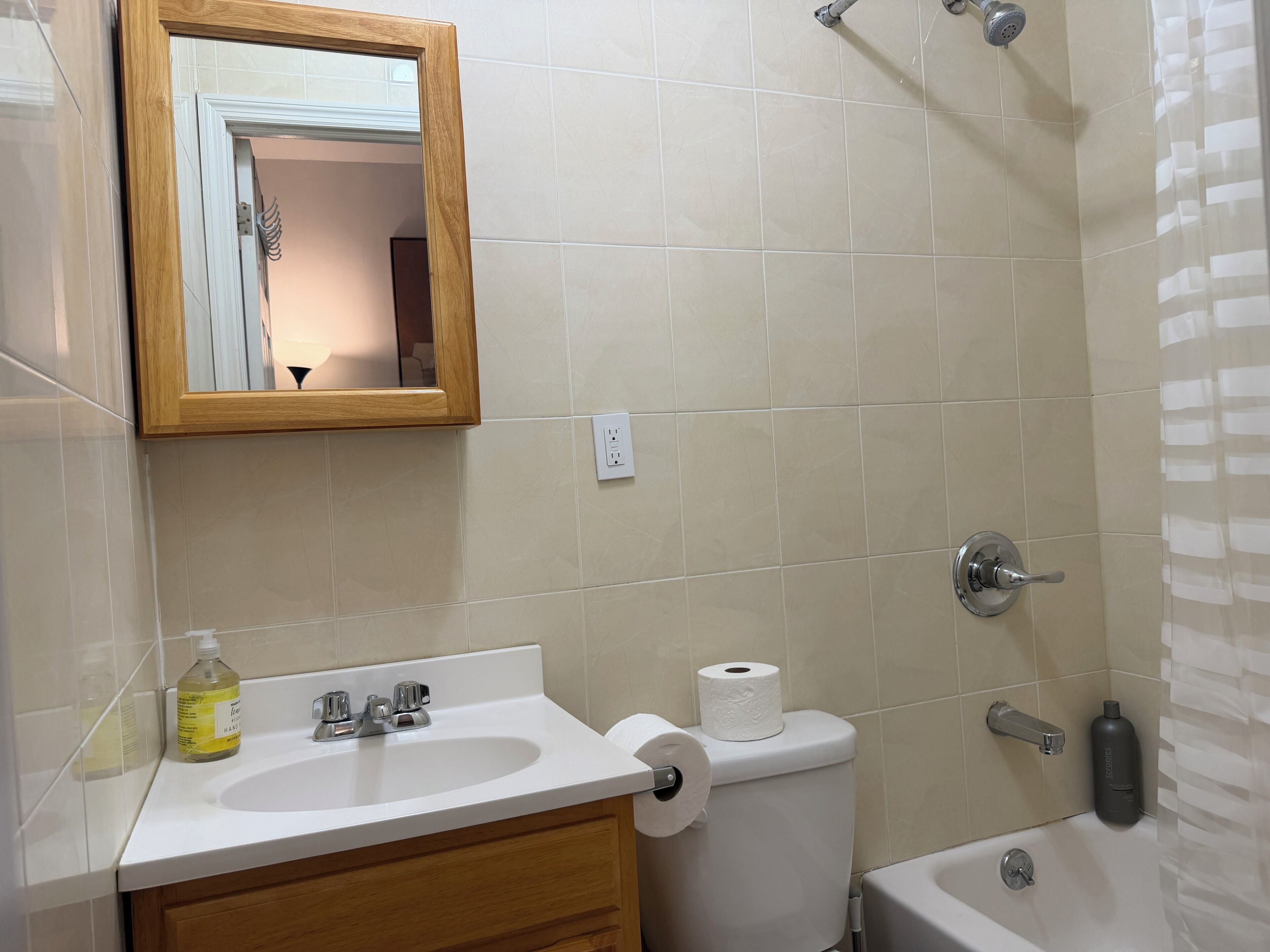 Une salle de bain avec un lavabo blanc, un miroir, des toilettes et une douche.