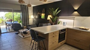 Cuina moderna amb una illa central, armaris de fusta i zona de menjador amb taula i cadires.