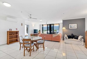 A spacious living area with a round dining table, a sofa, and a couch. - Belle Escapes Ships & Sips (Cairns)