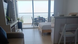A modern living room with a sofa, a bed, a dining area, and a balcony with a view. - Azul infinite... apartasuit in beautiful Cartagena (Cartagena de Indias)
