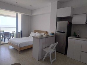 Ein modernes Schlafzimmer mit Bett, einer kleinen Küchenzeile und einem Essbereich mit Tisch und Stühlen.