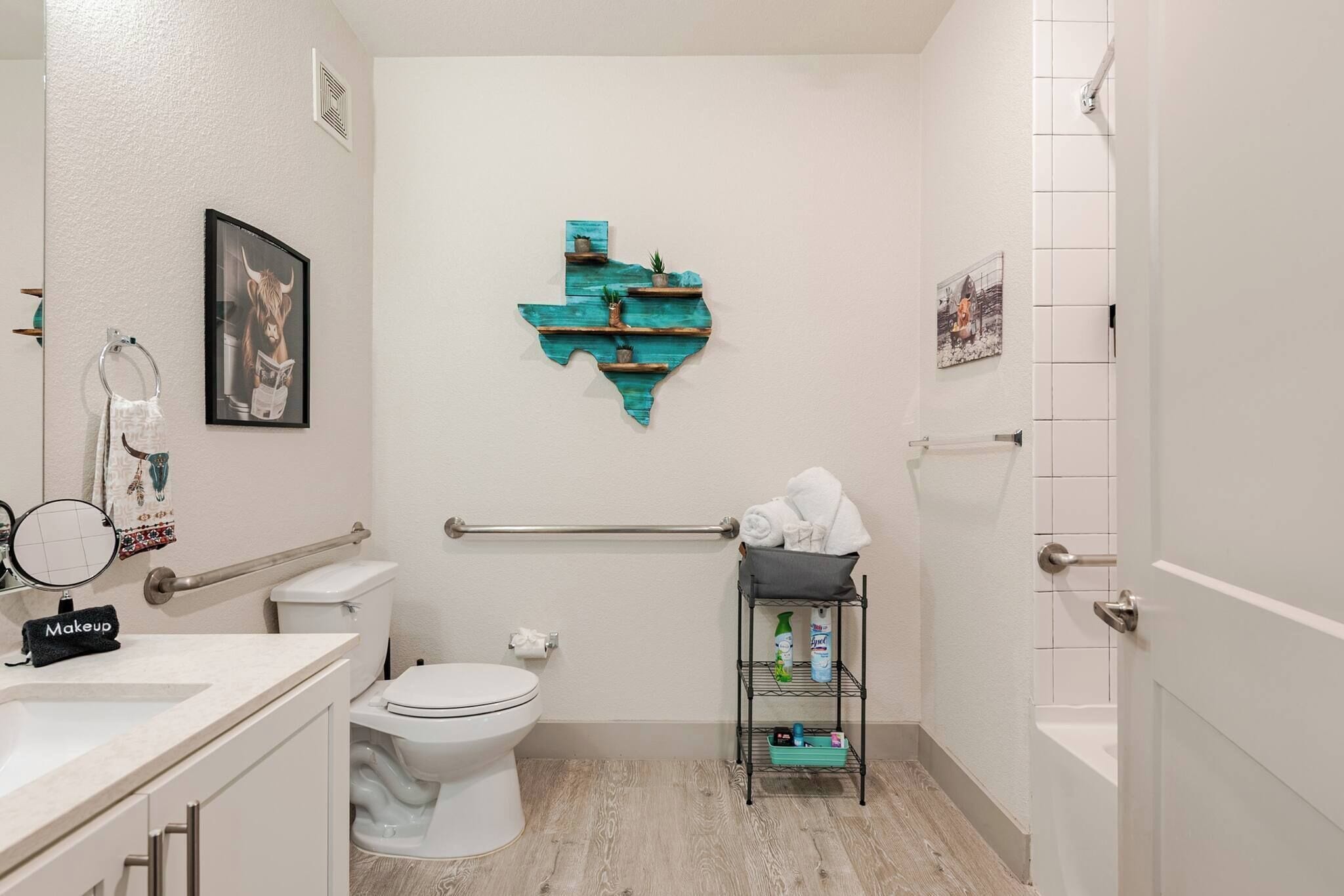 Une salle de bain comprenant des toilettes, un lavabo, un meuble-lavabo, un porte-serviettes et une étagère avec des articles de toilette.