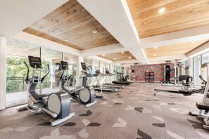 Un gimnasio con cintas de correr, elípticas y equipo de pesas.