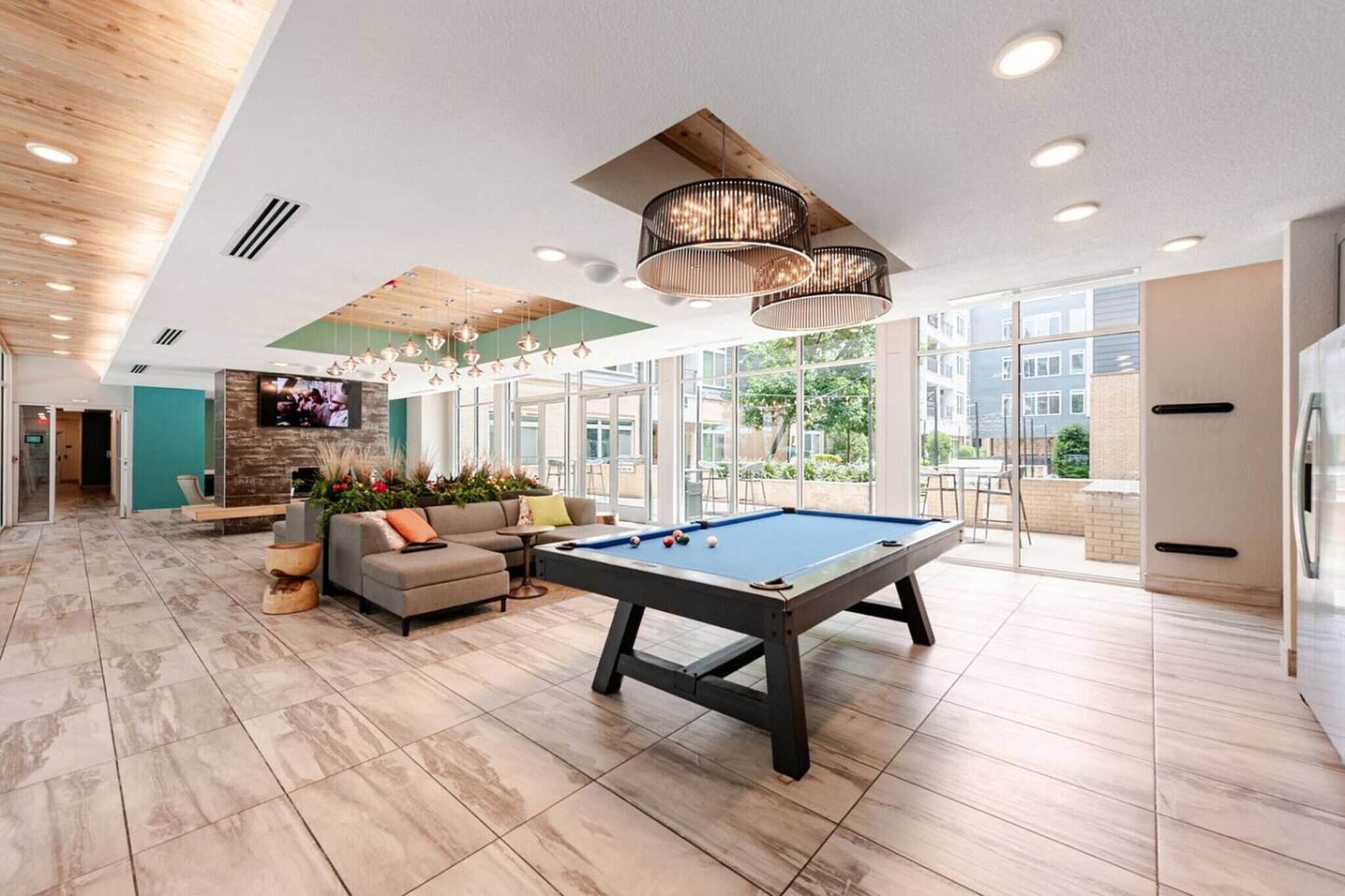 A spacious indoor area with a pool table, comfortable seating, and large windows offering natural light.