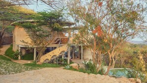A rustic building with a staircase leading to a porch, surrounded by greenery and a cobblestone path. - Winterfell by Sanctity Ferme Stays (Shoolagiri)